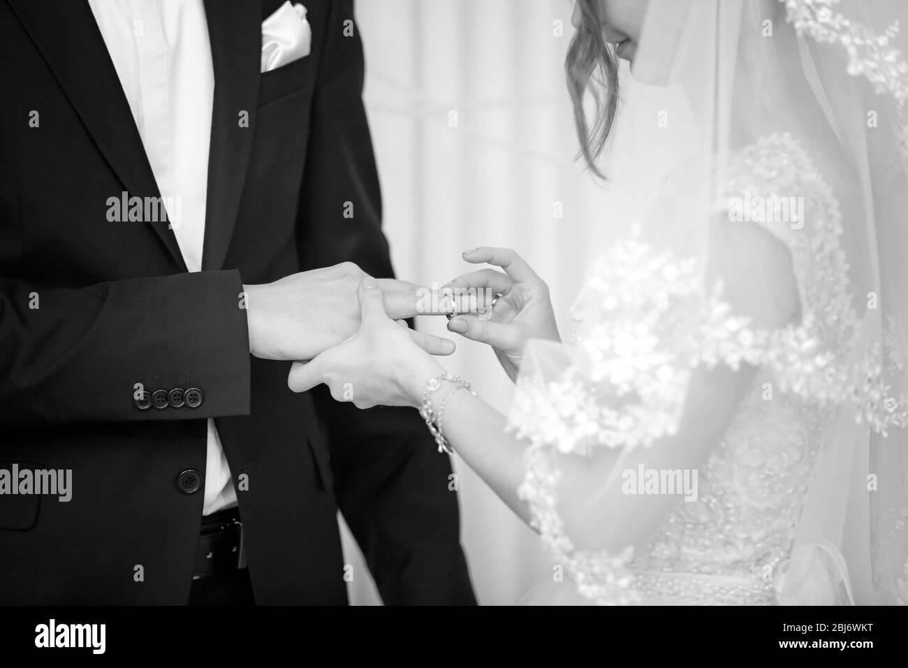 Sposa mettendo un anello sul dito dello sposo Foto Stock