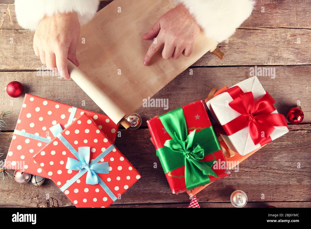 Un elenco di auguri di Natale in mani, regali e giocattoli di Babbo Natale su sfondo di legno Foto Stock