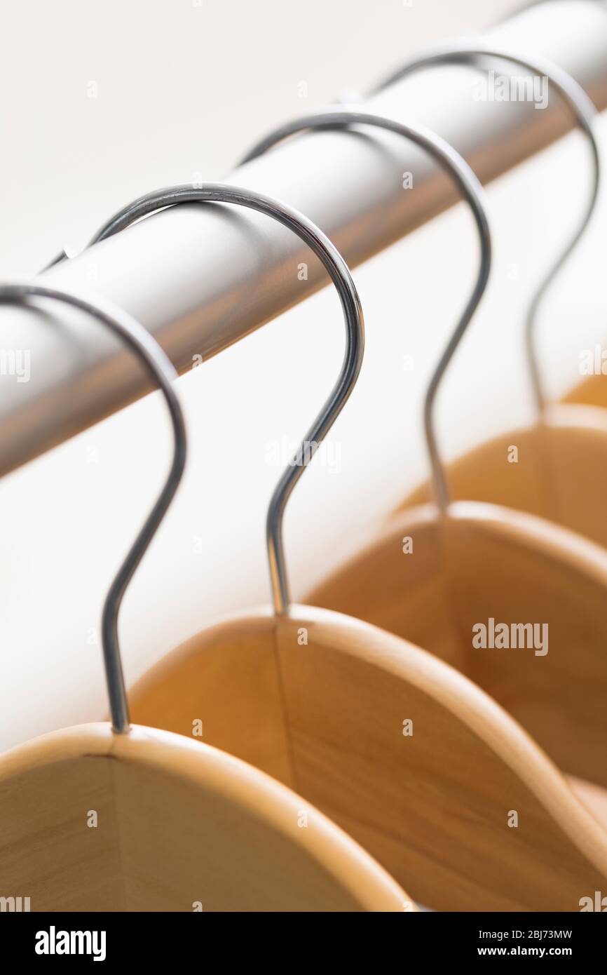 Appendiabiti in legno disposti in modo ordinato su un rack d'argento in una sala ben illuminata che mostra un design e un'organizzazione minimalisti Foto Stock