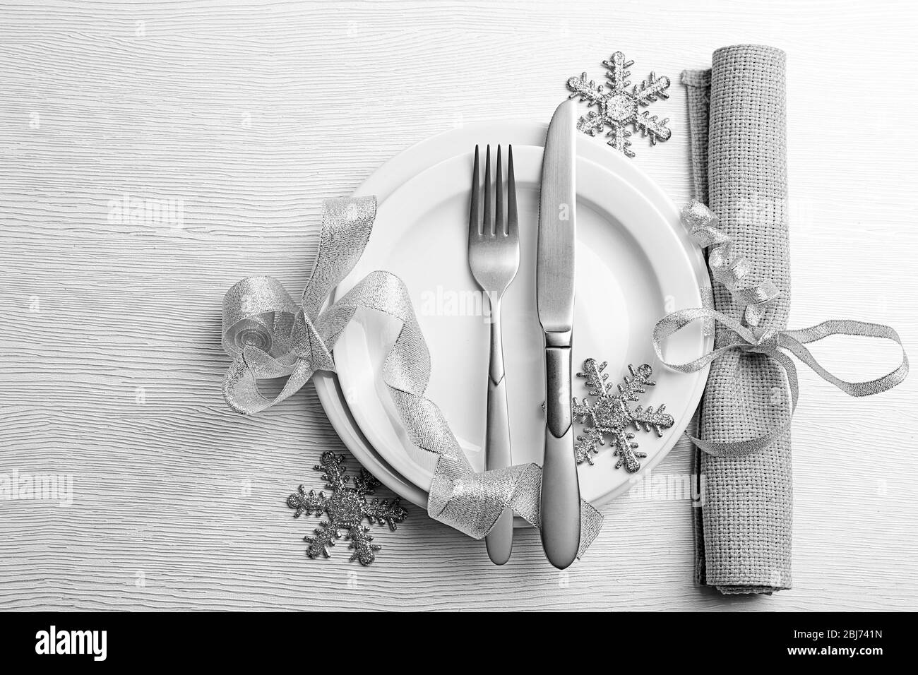 Posate di Natale su piatto e tovagliolo su tavolo di legno chiaro Foto Stock