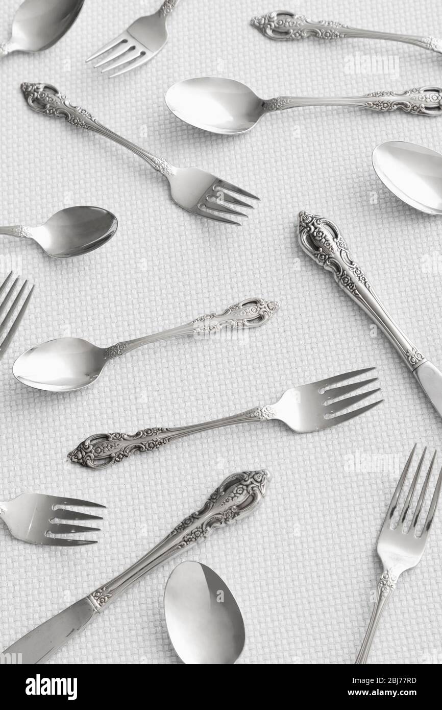 Collezione di posate in argento disposte artisticamente su una superficie ruvida durante la preparazione della tavola Foto Stock