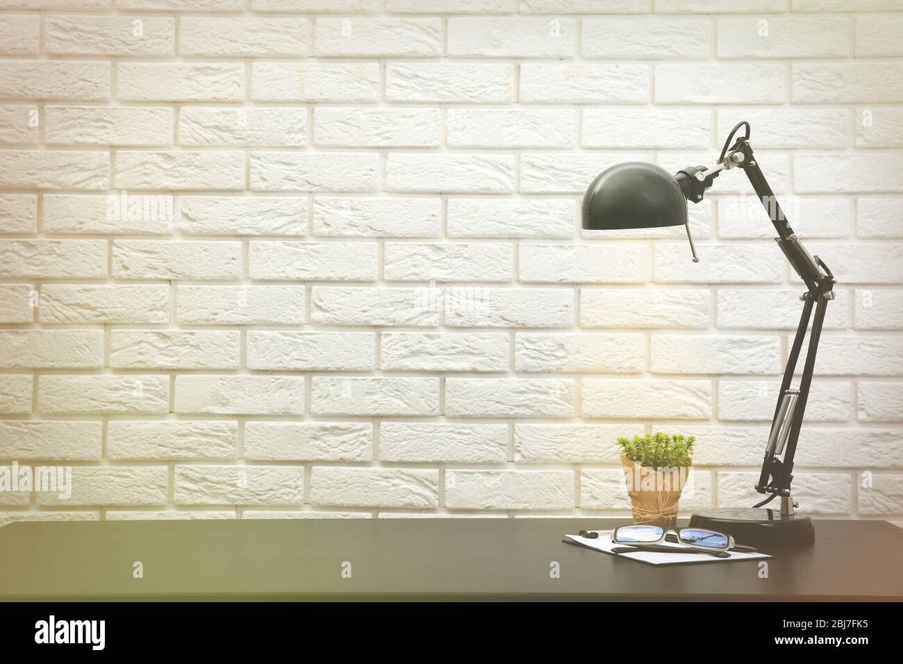 Lampada da ufficio sulla scrivania su parete di mattoni di fondo Foto Stock