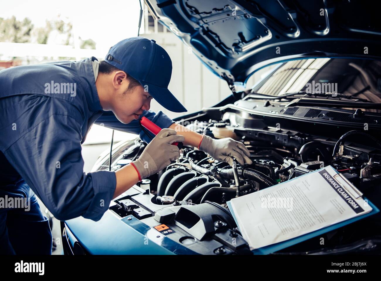 Autofficine tecnico tenendo la torcia elettrica controllo motore con checklist appunti per Veicolo per manutenzione da parte del cliente secondo la rivendicazione ordine nel negozio di riparazioni auto Foto Stock