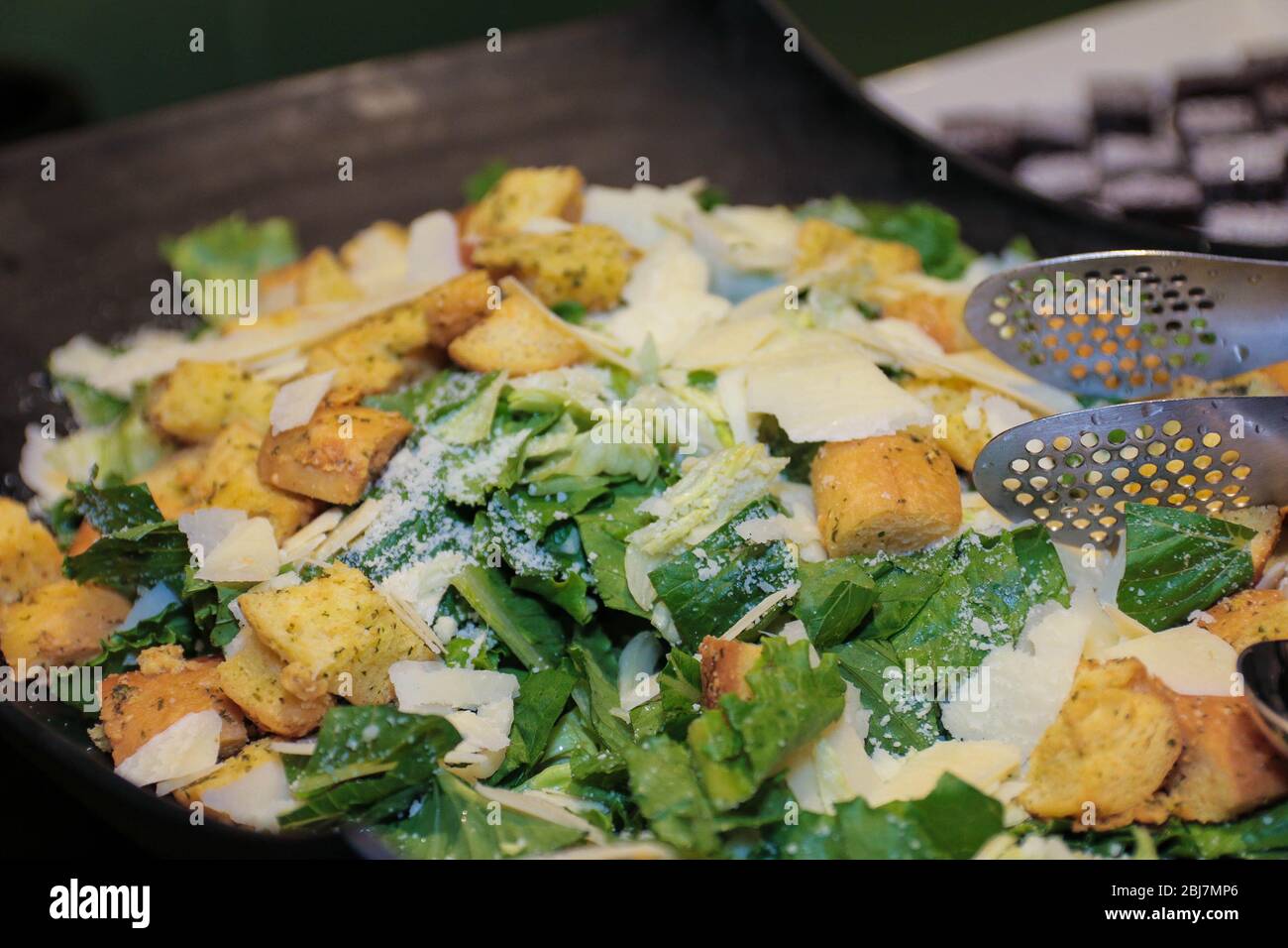 Insalata verde con tofu fritto in una ciotola nera. Insalata di tofu asiatica marinata al buffet del ristorante. Foto Stock