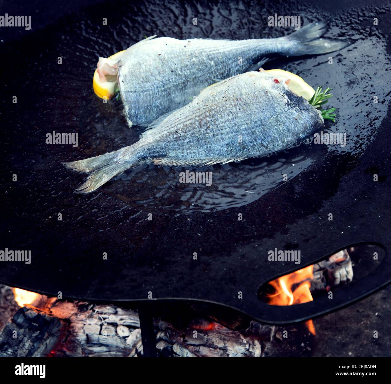 Primo piano di pesce alla griglia e gamberi su nero in padella all'aperto. Vista dall'alto Foto Stock