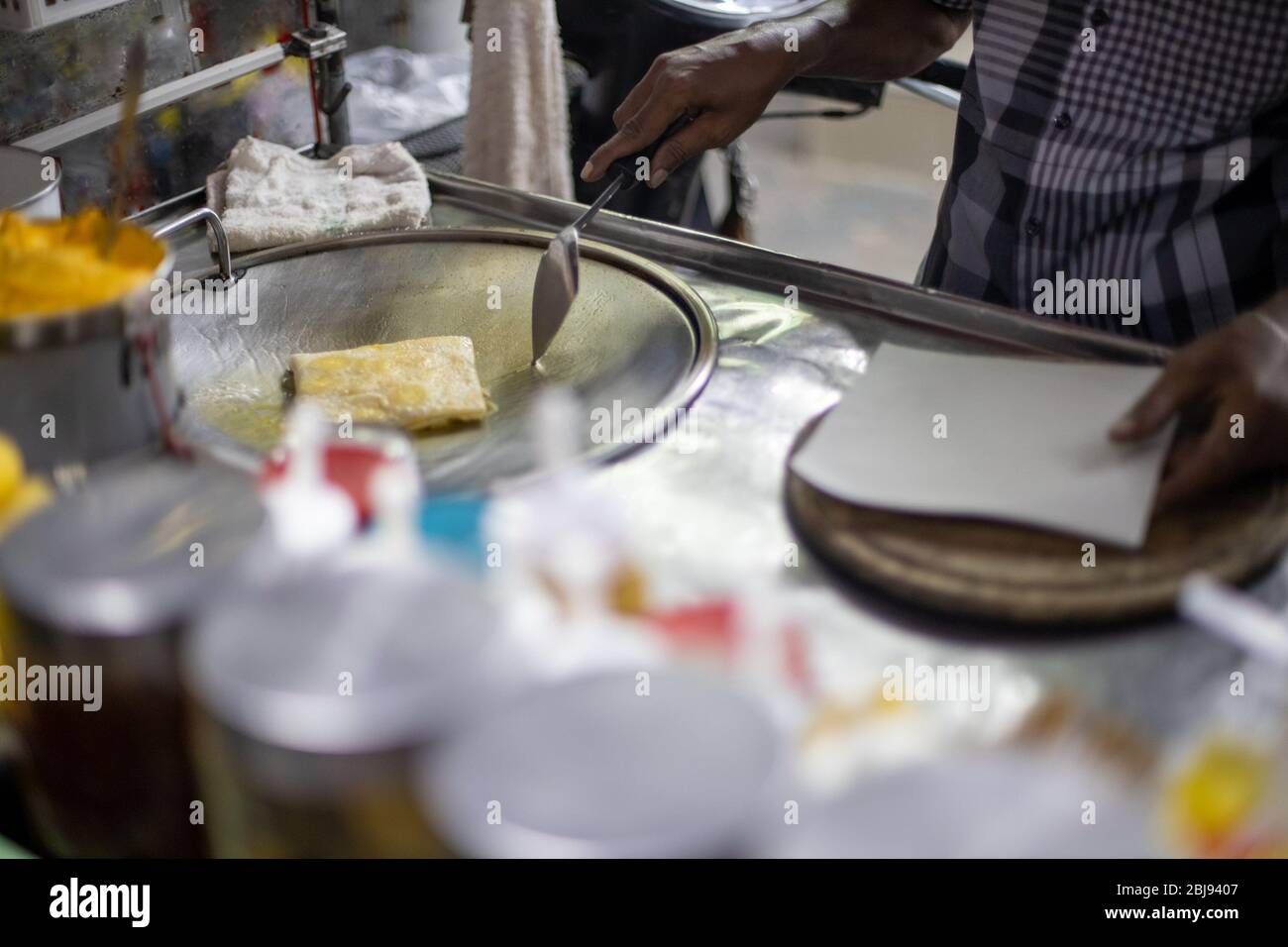 Mani di venditori di strada che cucinano il pane thai di roti dolce su una padella di acciaio o su una padella piatta grande. Gustatevi il cibo di strada della Thailandia. Foto Stock