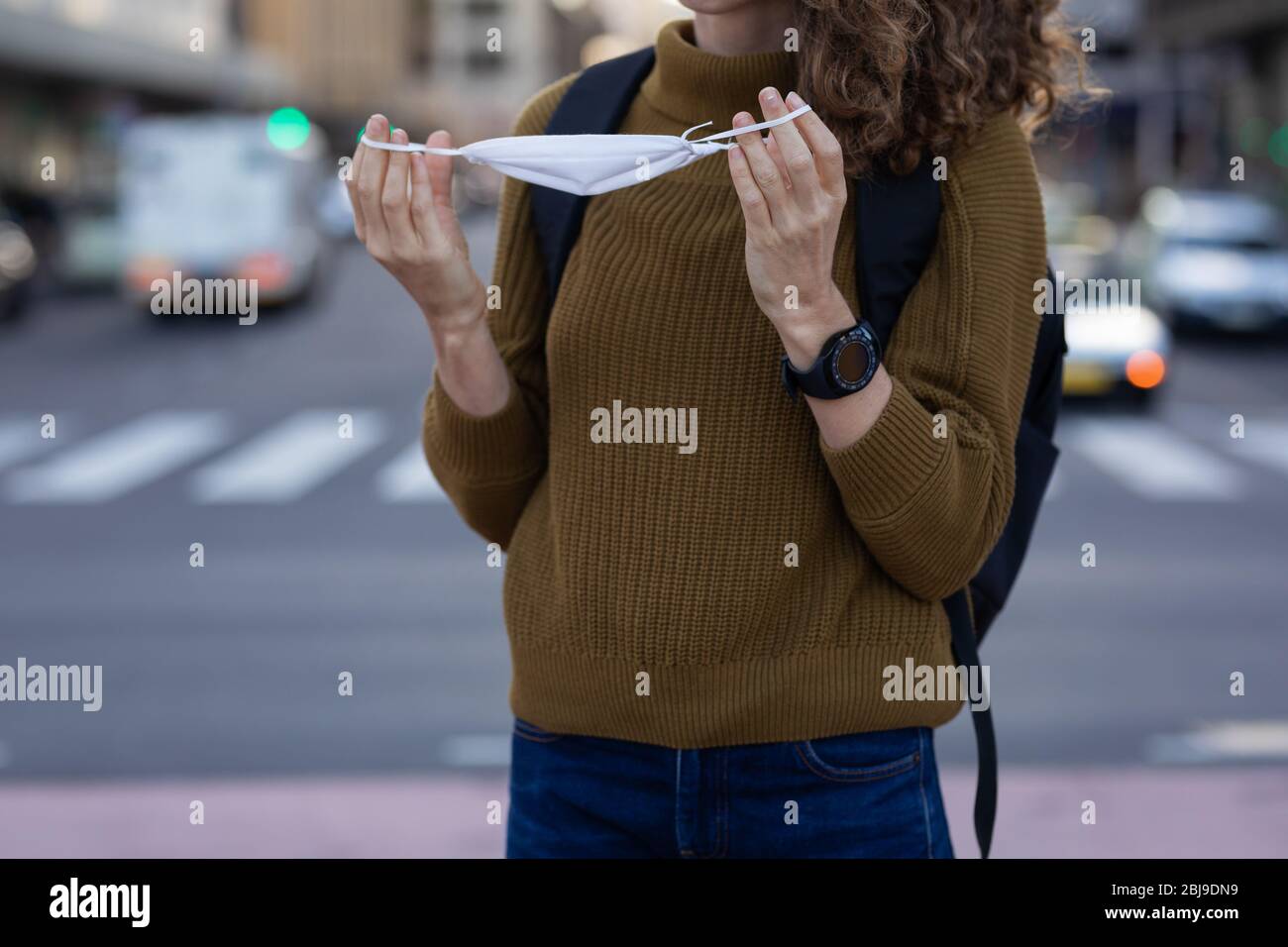 Donna caucasica che mette una maschera protettiva per le strade Foto Stock