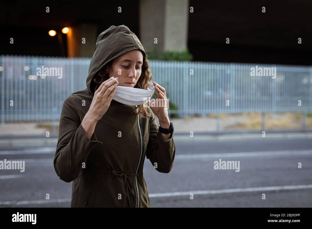 Donna caucasica che mette una maschera protettiva per le strade Foto Stock