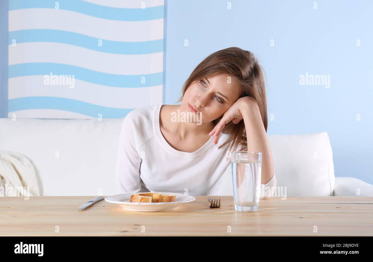 Giovane ragazza depressa con disordine di mangiare a tavola di legno Foto Stock
