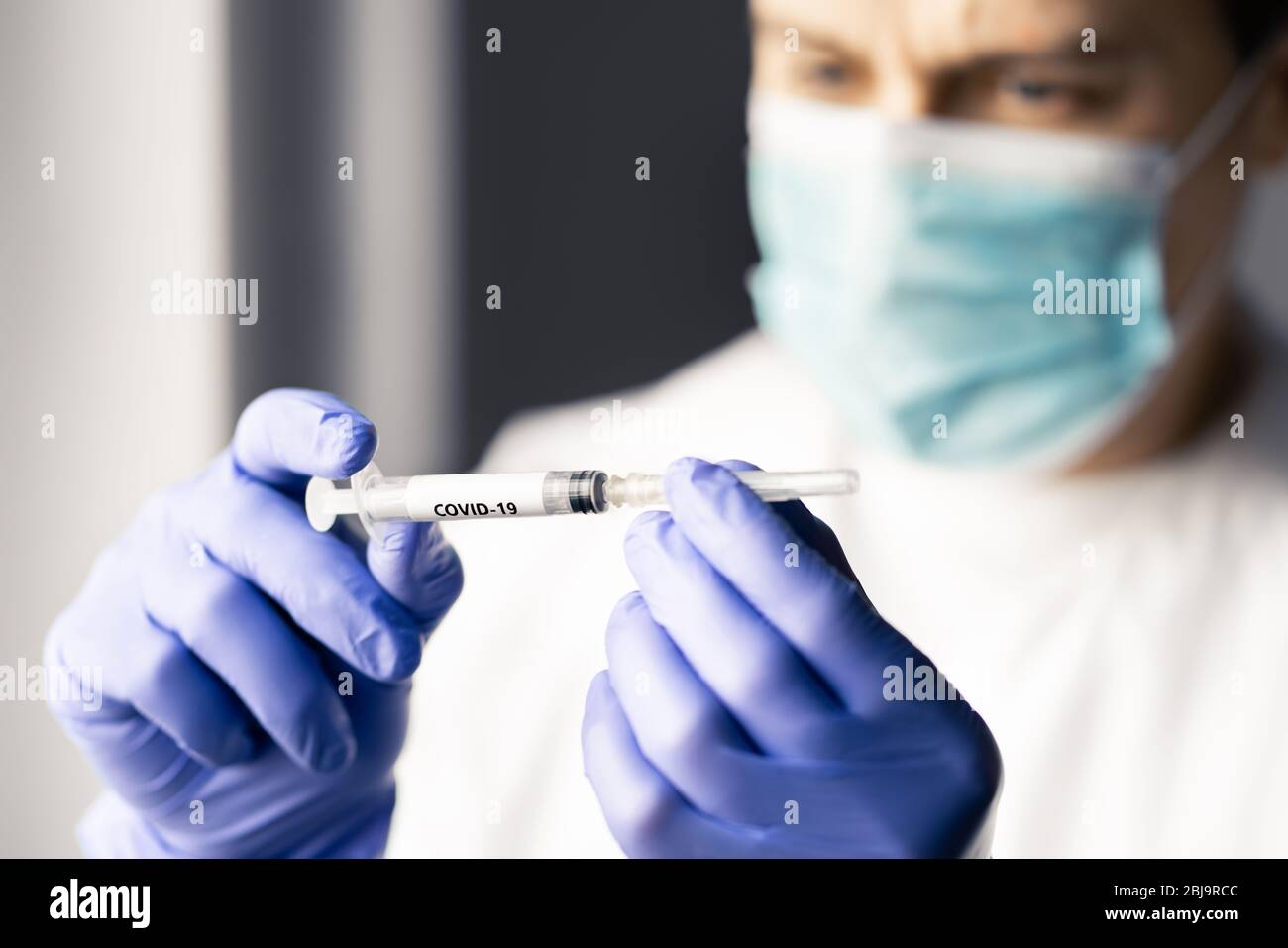 Medico o infermiere che osservi un ago della siringa per il vaccino contro il coronavirus. Medico professionista o scienziato che lavora in laboratorio per la ricerca. Foto Stock