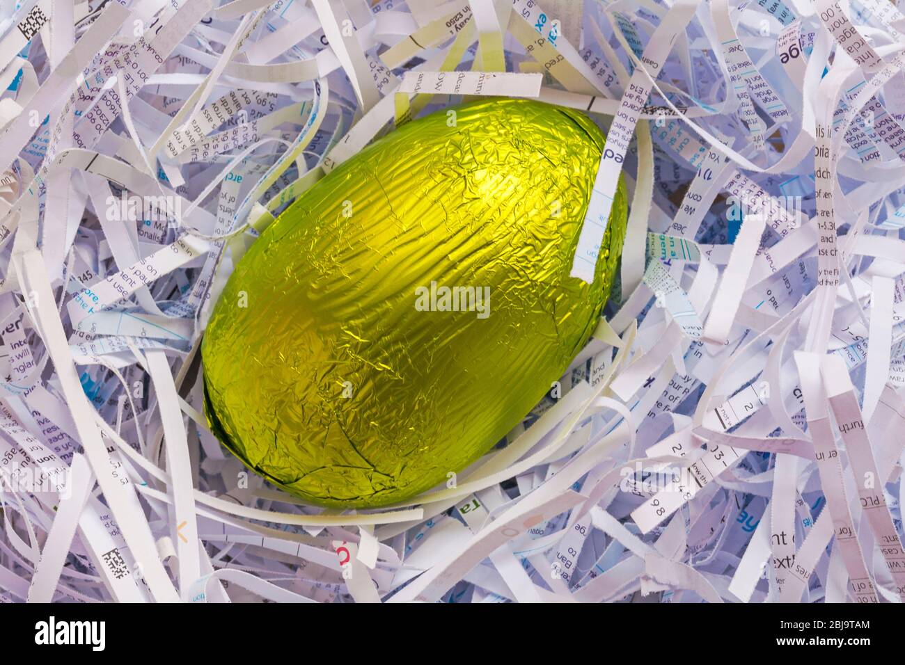Foil avvolto uovo di Pasqua in nido di carta grattugiata - concetto di uovo di nido, sicurezza Foto Stock
