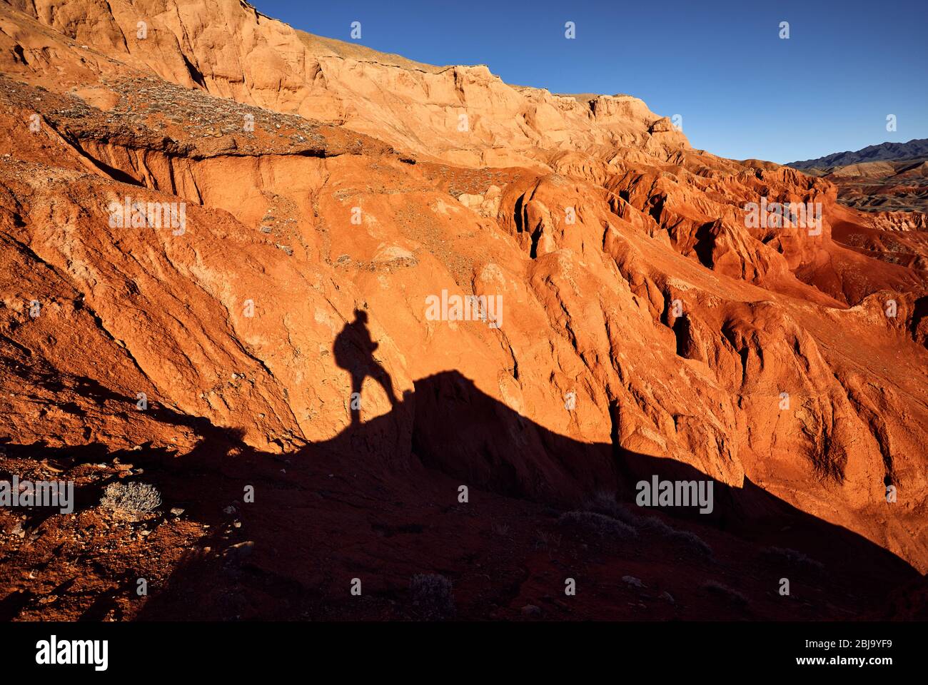 Ombra turistica a monti rossi nel canyon del deserto contro il cielo blu in Kazakistan Foto Stock