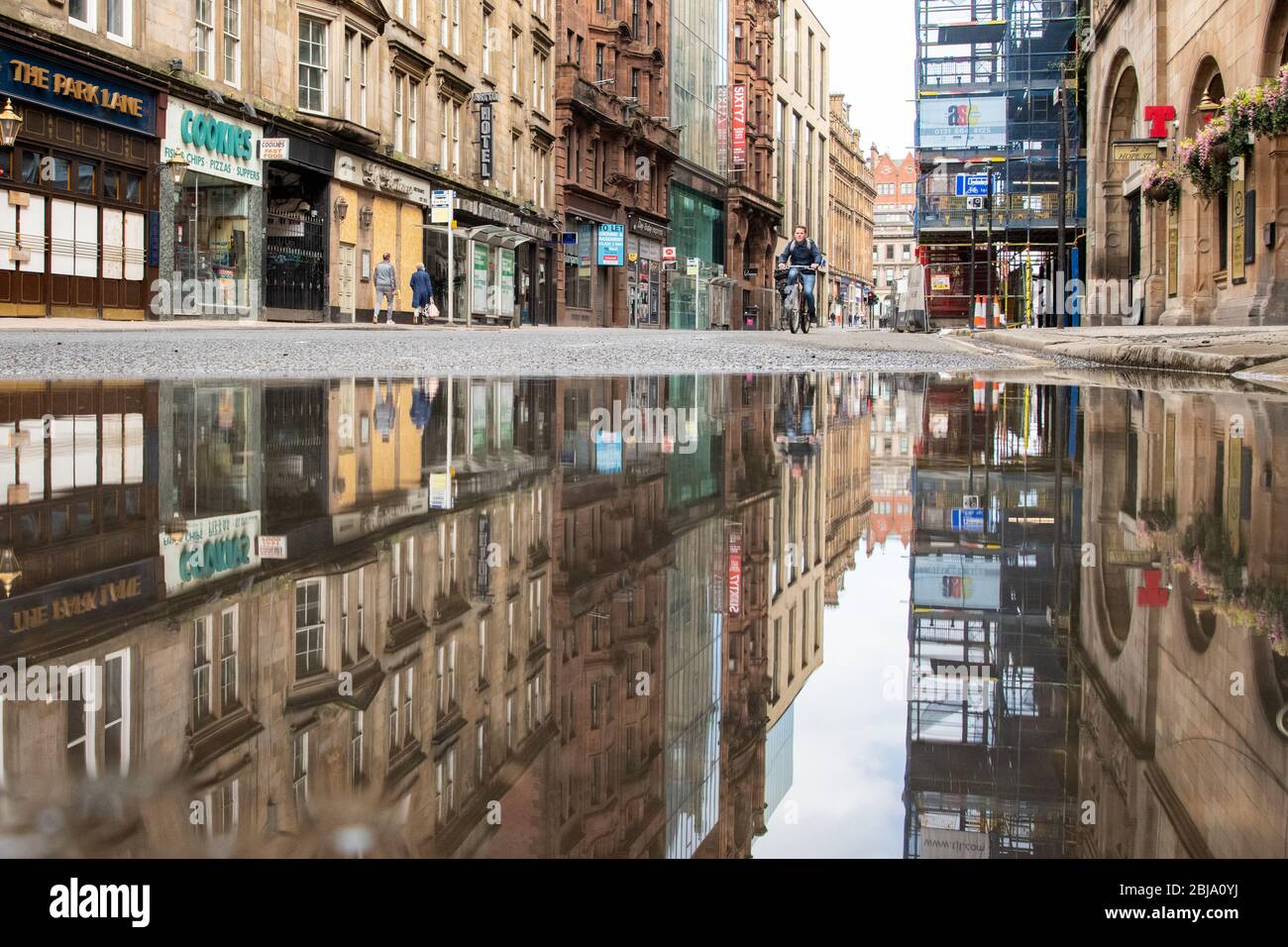 Ciclista e pedoni su una tranquilla Hope Street che porta a ridurre l'inquinamento durante l'abbattimento dei coronavirus nel centro di Glasgow, Scozia, Regno Unito Foto Stock