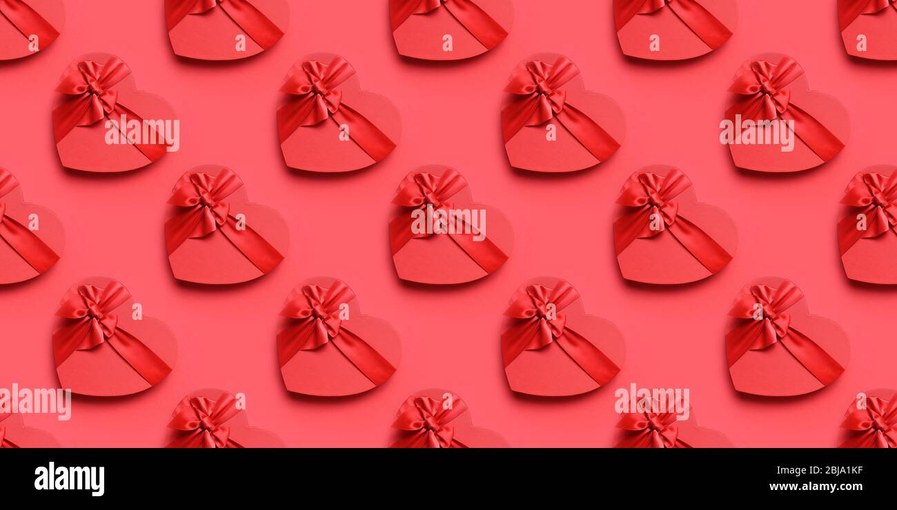 Scatola regalo a forma di cuore con arco rosso su rosso. Ripetizione senza giunture. Banner. Amore e sentimenti. Biglietto di auguri. Grandi sconti. Foto Stock