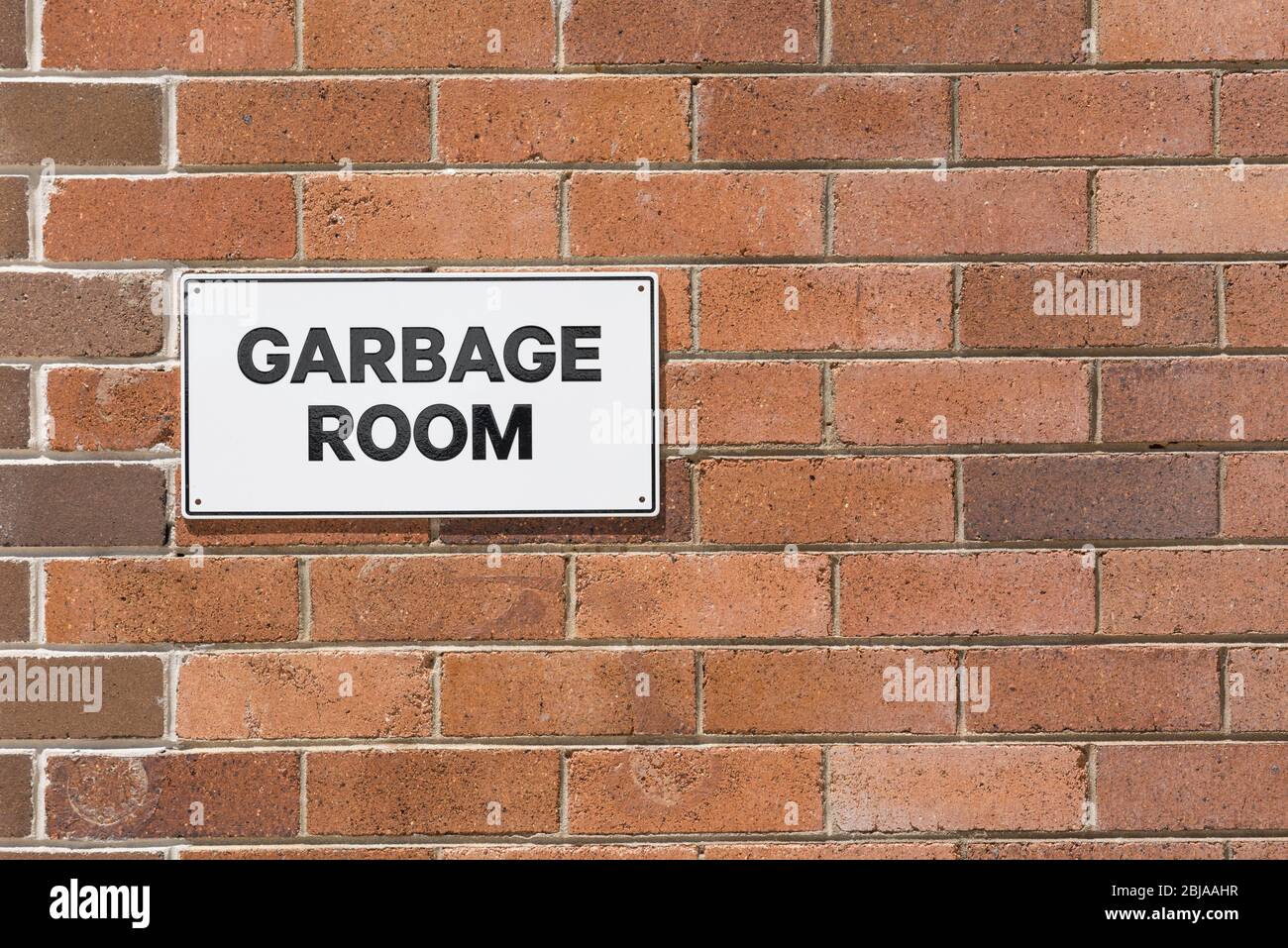 Un muro bicolore in mattoni con un cartello nero e bianco Garbage Room Foto Stock