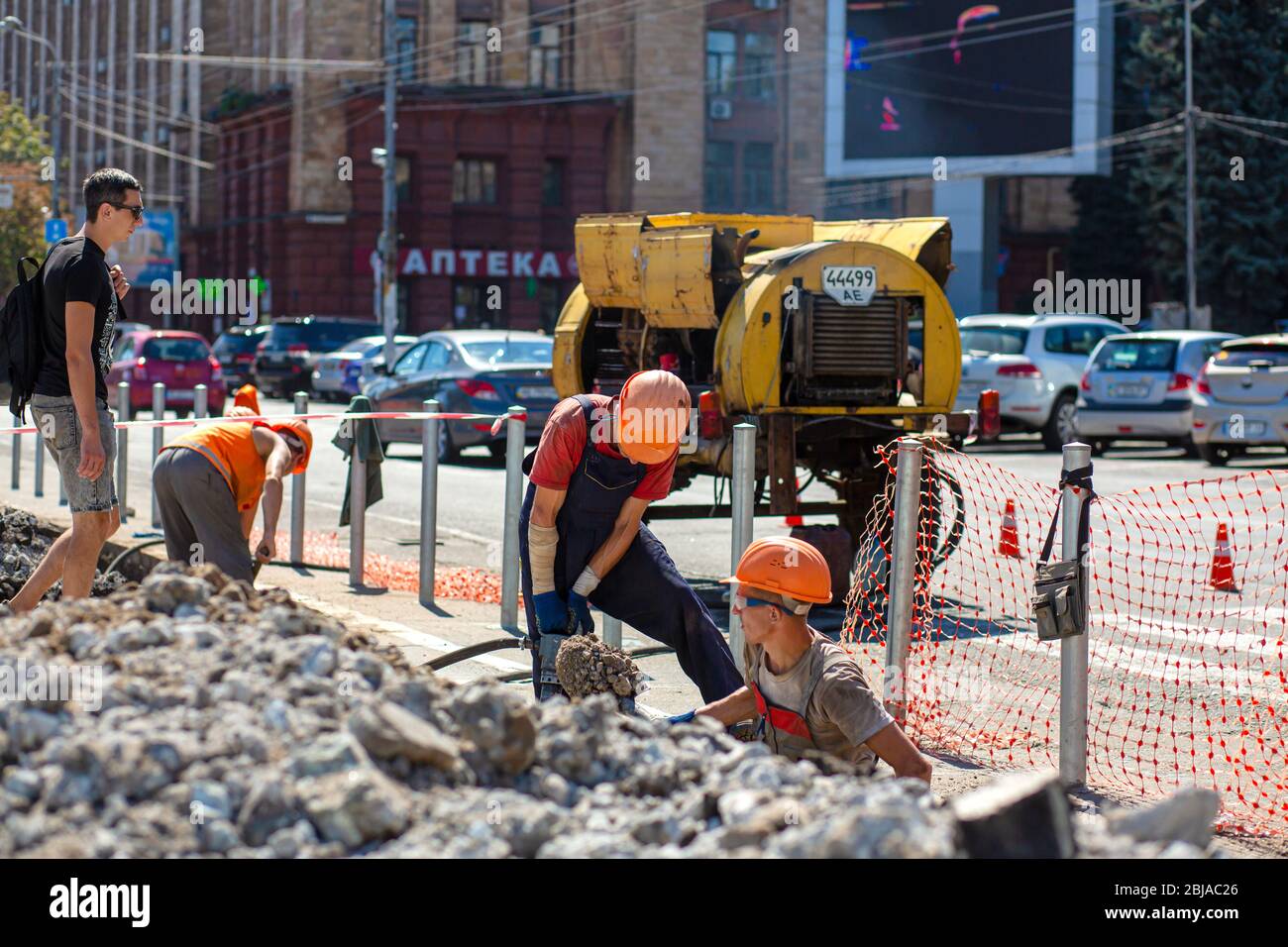 Lavori di riparazione sulla strada della città. I lavoratori professionisti smontano parte della strada con un utensile professionale. Lavoratori rimuovere l'asfalto e scavare un buco. T Foto Stock