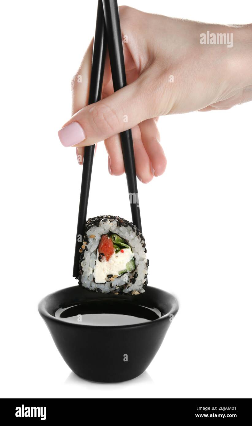 Femmina mano tenendo delizioso sushi rotolo con bacchette, isolato su bianco Foto Stock