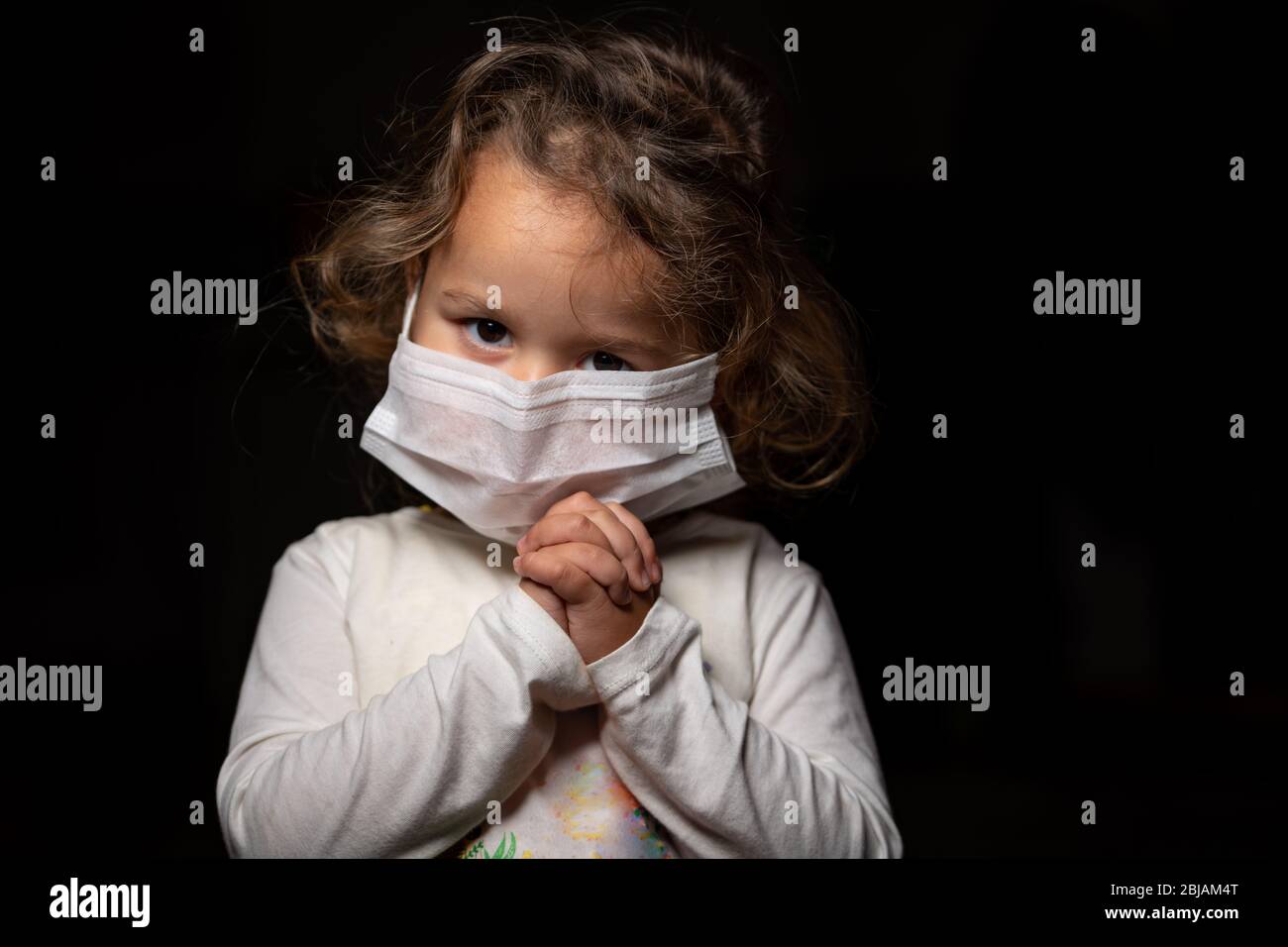 Ragazza che indossa maschera per la protezione contro la pandemia di coronavirus Covid-19. Sta pregando Dio per una cura e un aiuto. Spazio di copia. Foto Stock