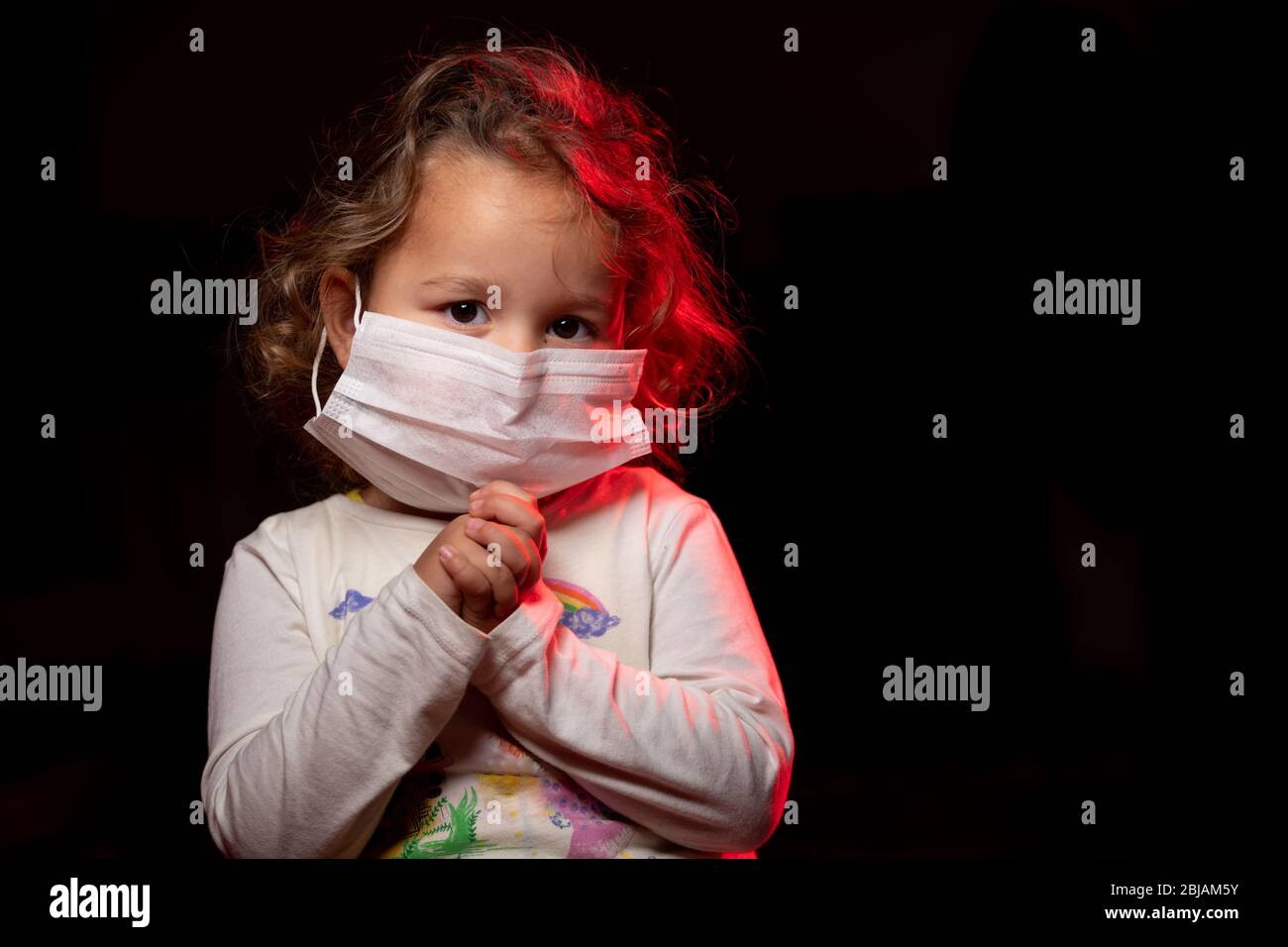 Ragazza che indossa maschera per la protezione contro la pandemia di coronavirus Covid-19. Sta pregando Dio per una cura e un aiuto. Spazio di copia. Foto Stock