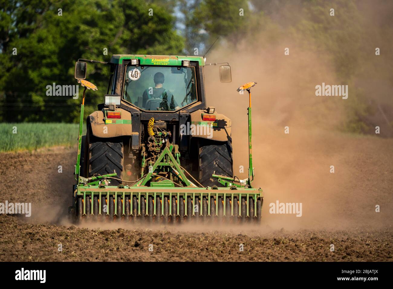 Coltivatore che lavora i campi in primavera, asciutto 2020 aprile, trattore tira nube spessa di polvere, mentre coltivando, allentando il terreno, dietro di lui, Niederrhein Foto Stock