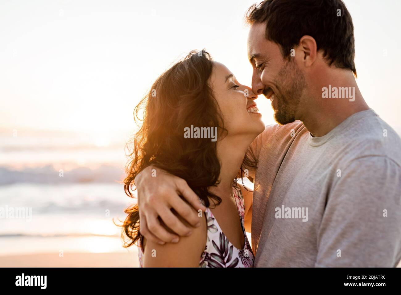 Affettuosa giovane coppia abbracciare su una spiaggia al tramonto Foto Stock