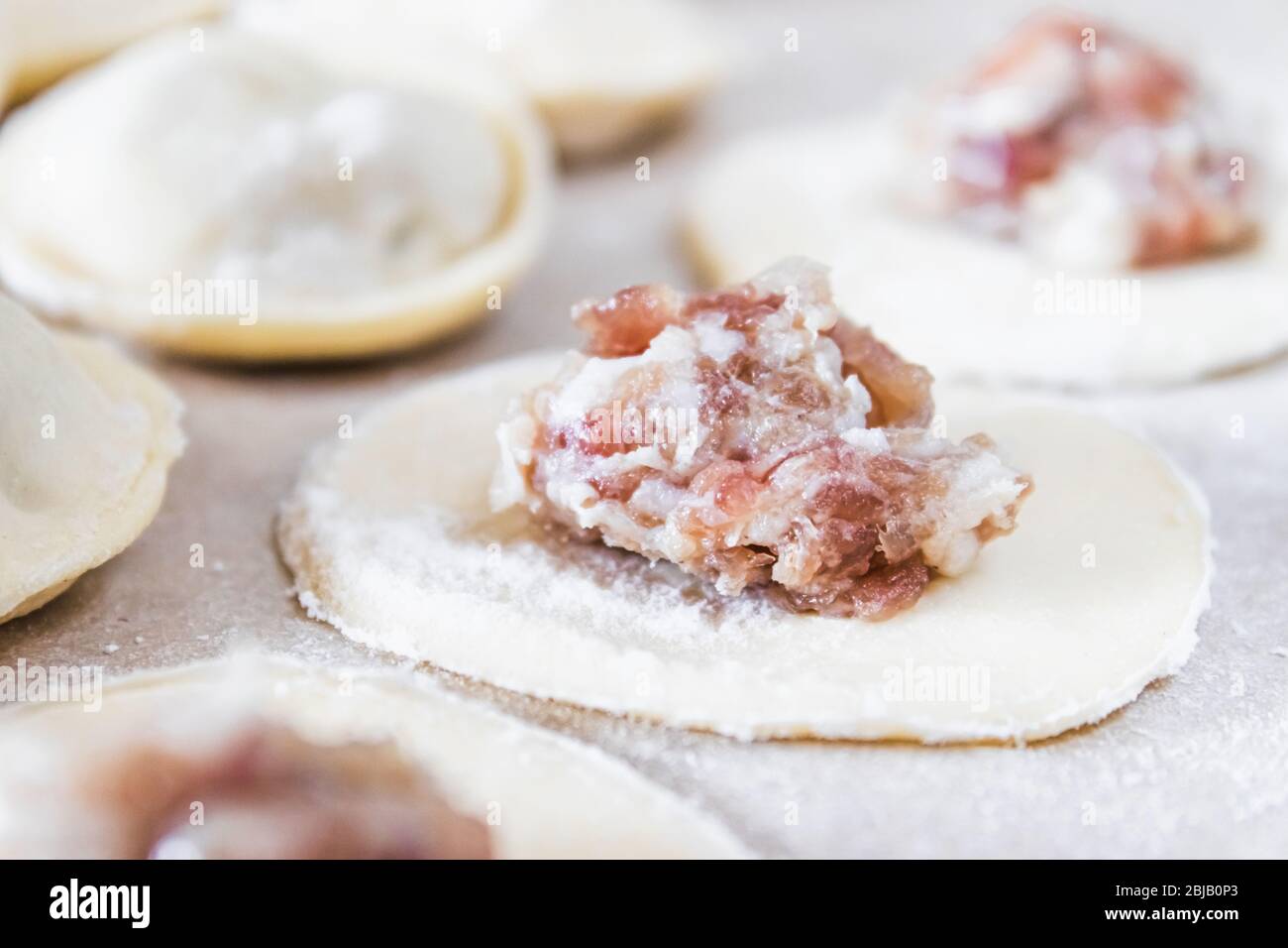 Il processo di fare gnocchi fatti in casa. Carne tritata sull'impasto, il processo di produzione di gnocchi fatti in casa. Cucina russa. Foto Stock