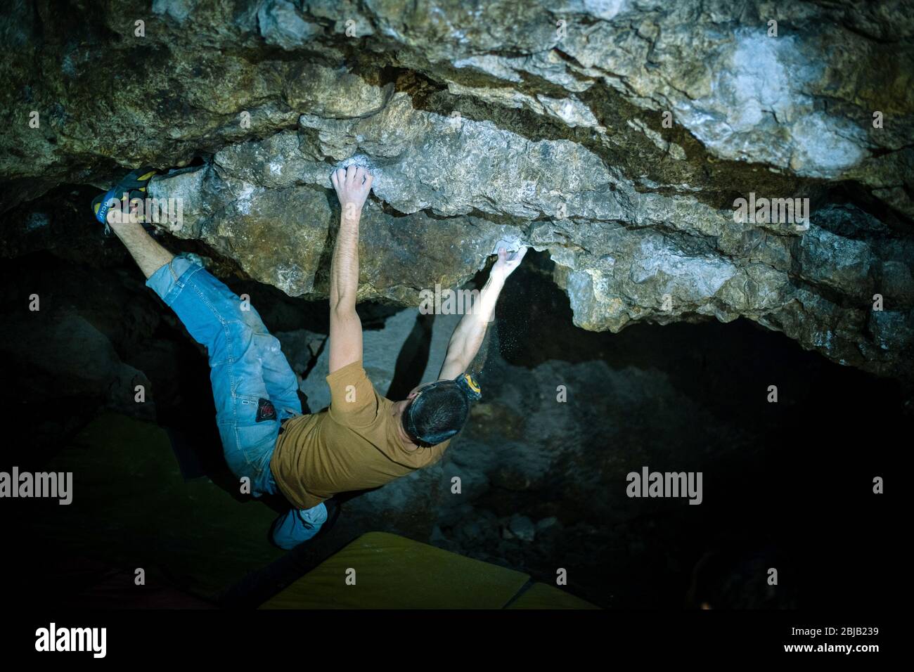 L'uomo sta facendo un masso nella grotta di Twardowski. Bouldering nella roccia. Grotta di Twardowski Foto Stock