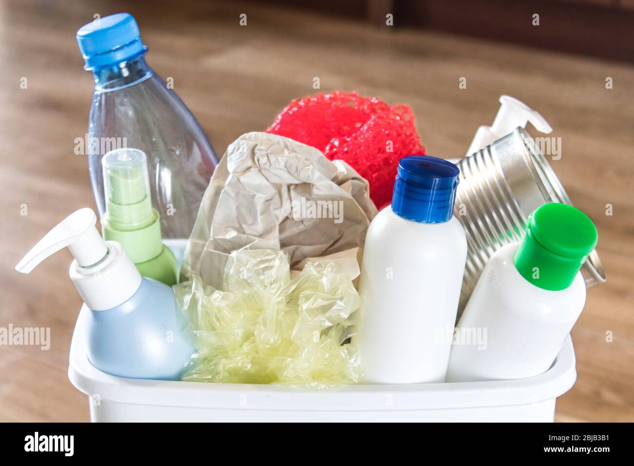 Cestino bianco con spazzatura domestica. Bottiglie di plastica e carta in un cestino. Cestino con spazzatura in cucina. Foto Stock