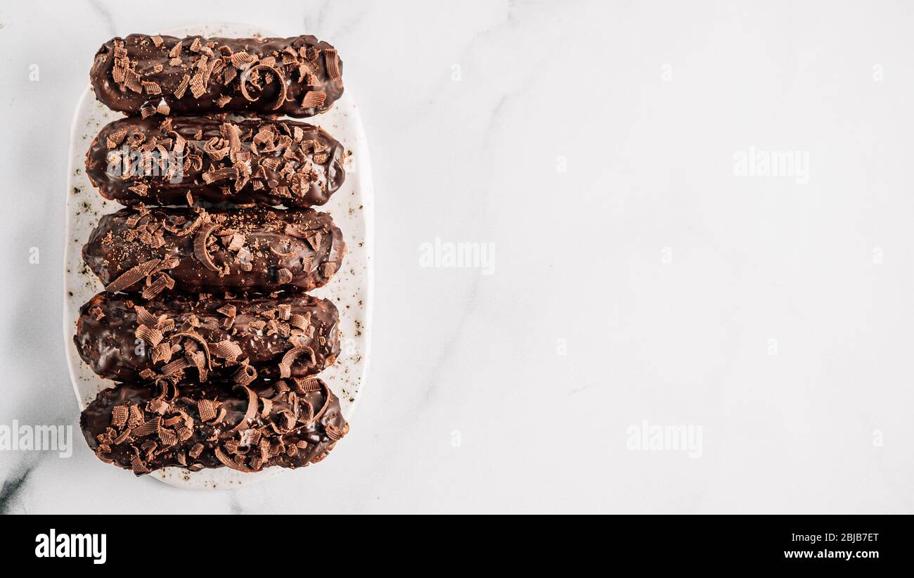 Set di airs fatti in casa con cioccolato su sfondo di marmo. Vista dall'alto di deliziosi e salutari profittatori con glassa al cioccolato. Copiare lo spazio per il testo o il disegno. Banner Foto Stock