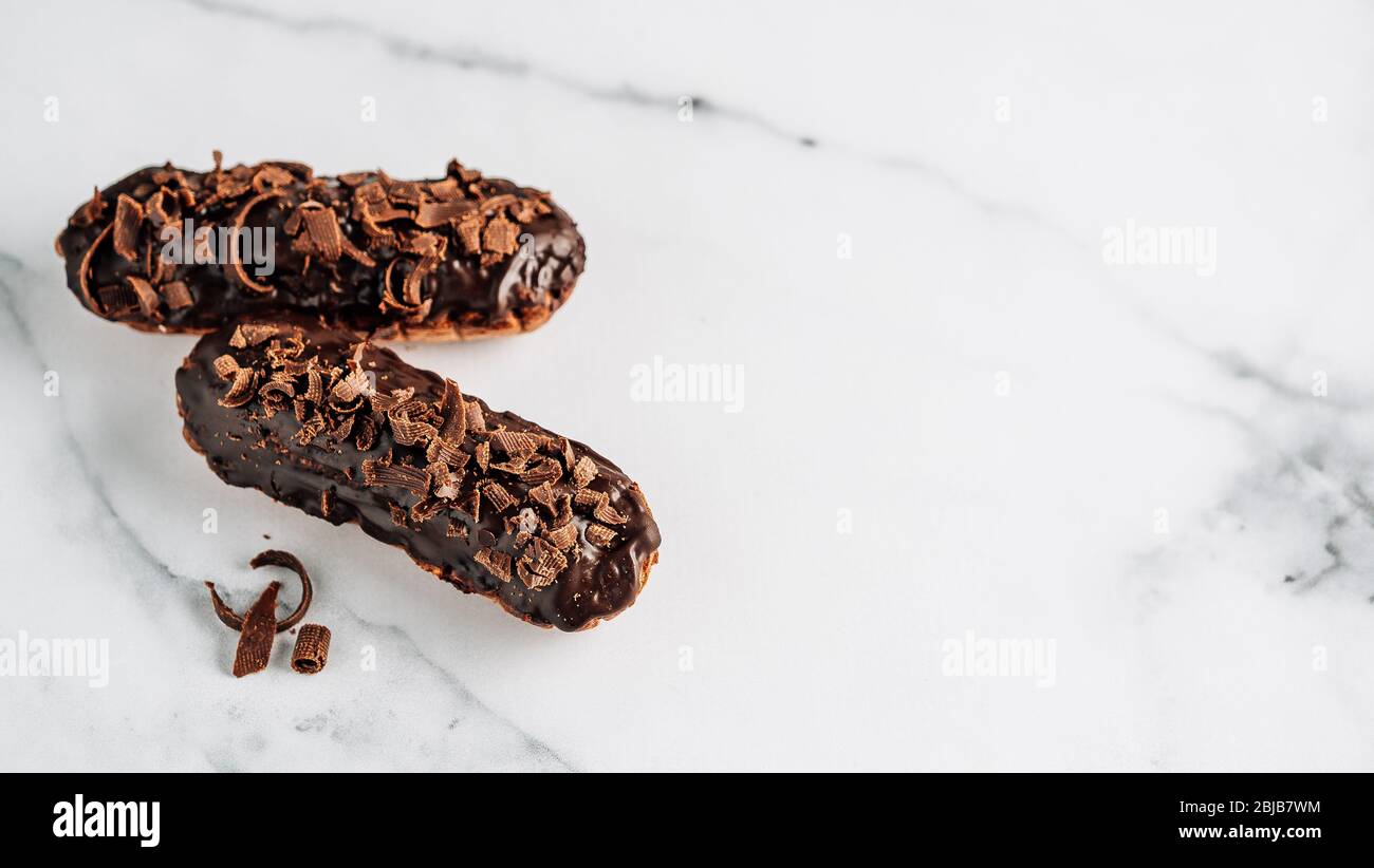 Set di eclairs fatti in casa con cioccolato bianco su sfondo marmo. Vista ravvicinata della deliziosa profitroles sani con glassa di cioccolato. Copia spazio per il testo o il design. Banner Foto Stock