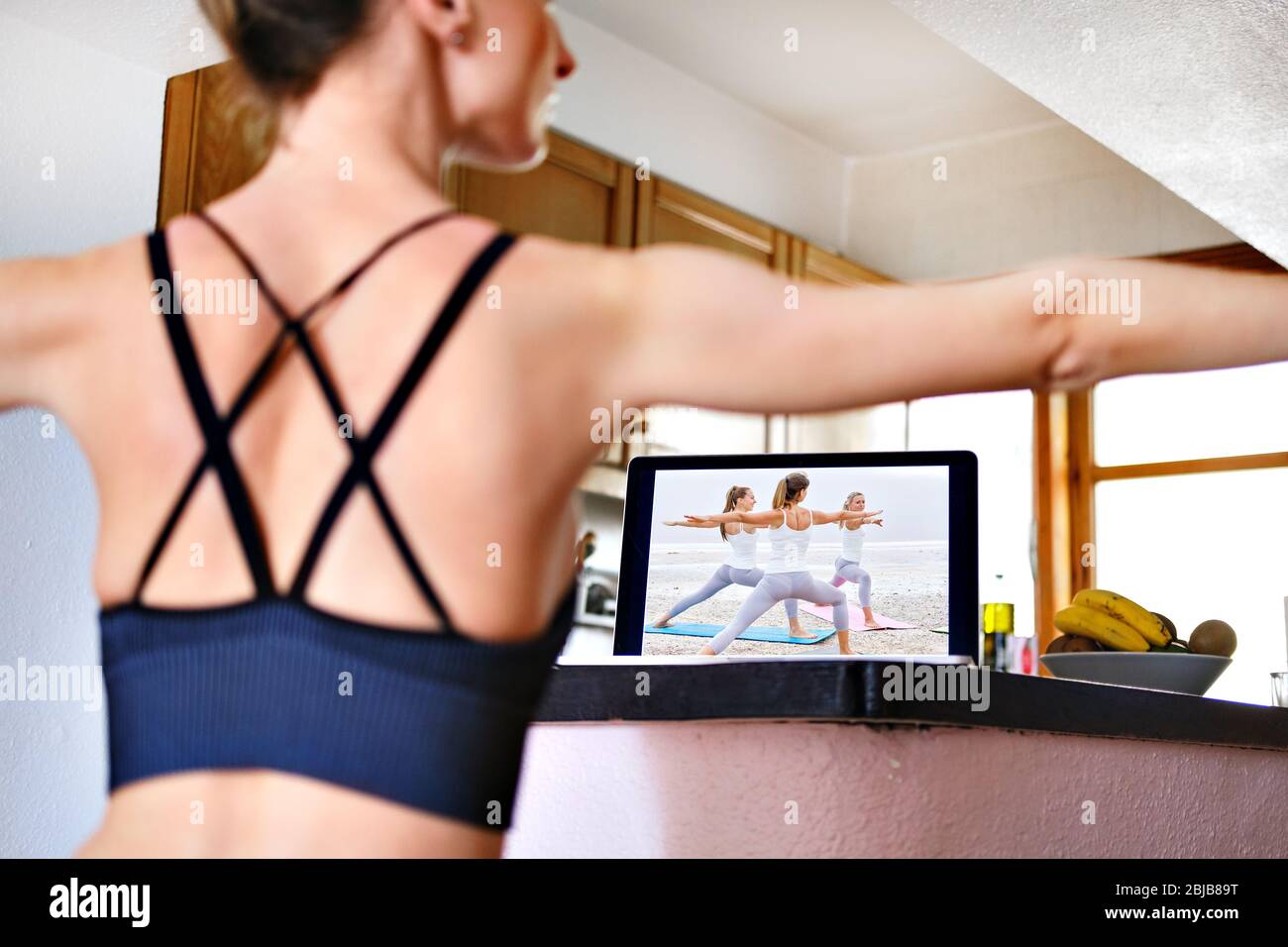Donna posteriore vista pratica esercizi yoga Guerriero 2 posa o Virabhadrasana posizione guardando on-line allenamento sullo schermo del notebook ripetere asanas. Ho Foto Stock