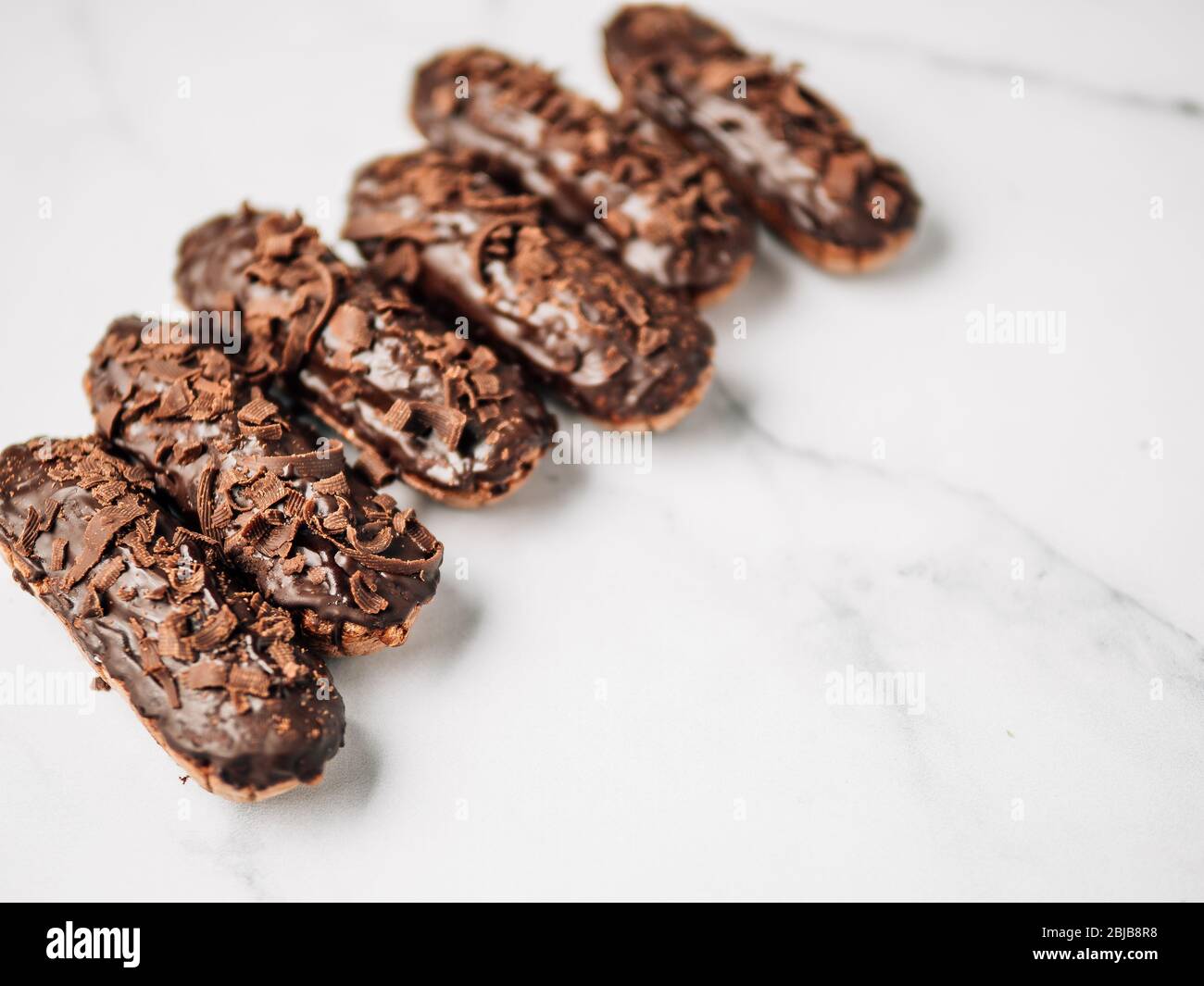 Set di eclairs fatti in casa con cioccolato su sfondo marmo. Vista ravvicinata della deliziosa profitroles sani con glassa di cioccolato. Copia spazio per il testo o per la progettazione Foto Stock
