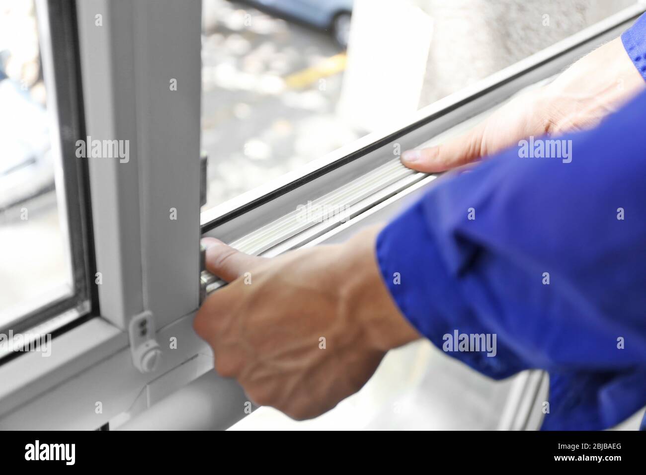 Addetto alle costruzioni che mette in casa il nastro di schiuma sigillante sulla finestra Foto Stock