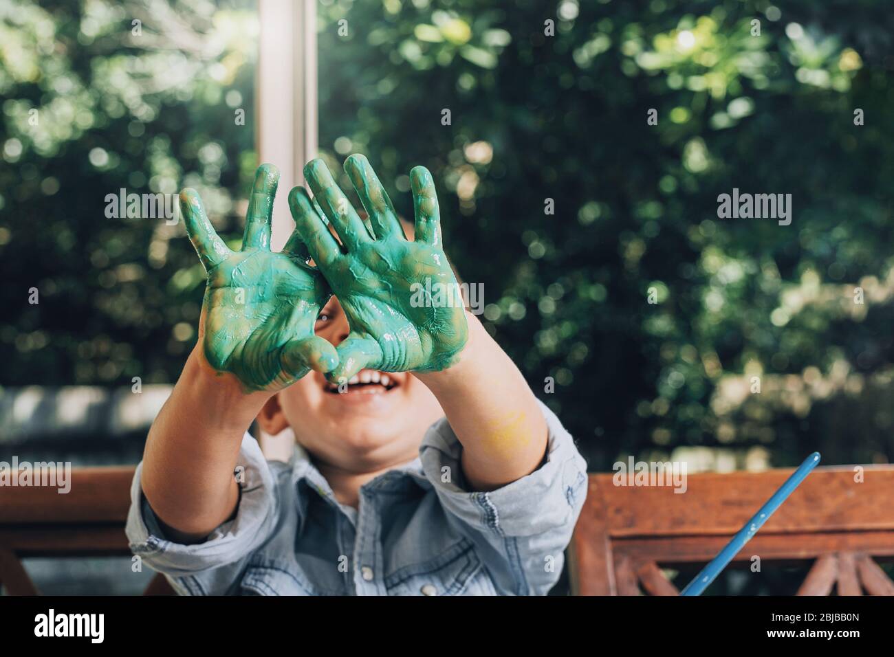 Ragazzo con mani dipinte in verde pronto a fare stampe a mano. Foto Stock