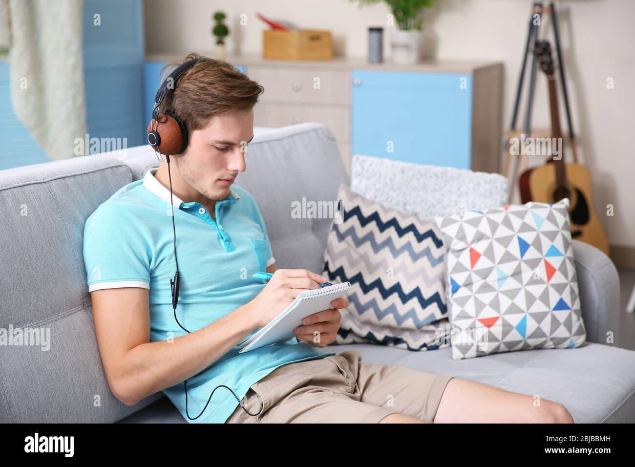 Giovane uomo che compone la canzone e seduto sul divano Foto stock - Alamy