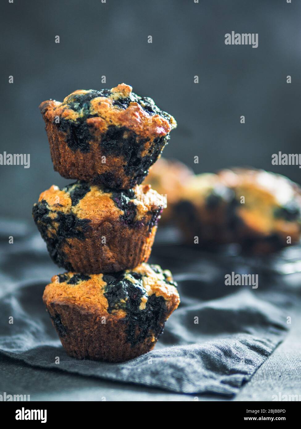 In casa vegan muffin ai mirtilli su sfondo scuro. Pila di tre uova muffin gratis con copia spazio per il testo o il design. Tasto basso. Verticale. Foto Stock