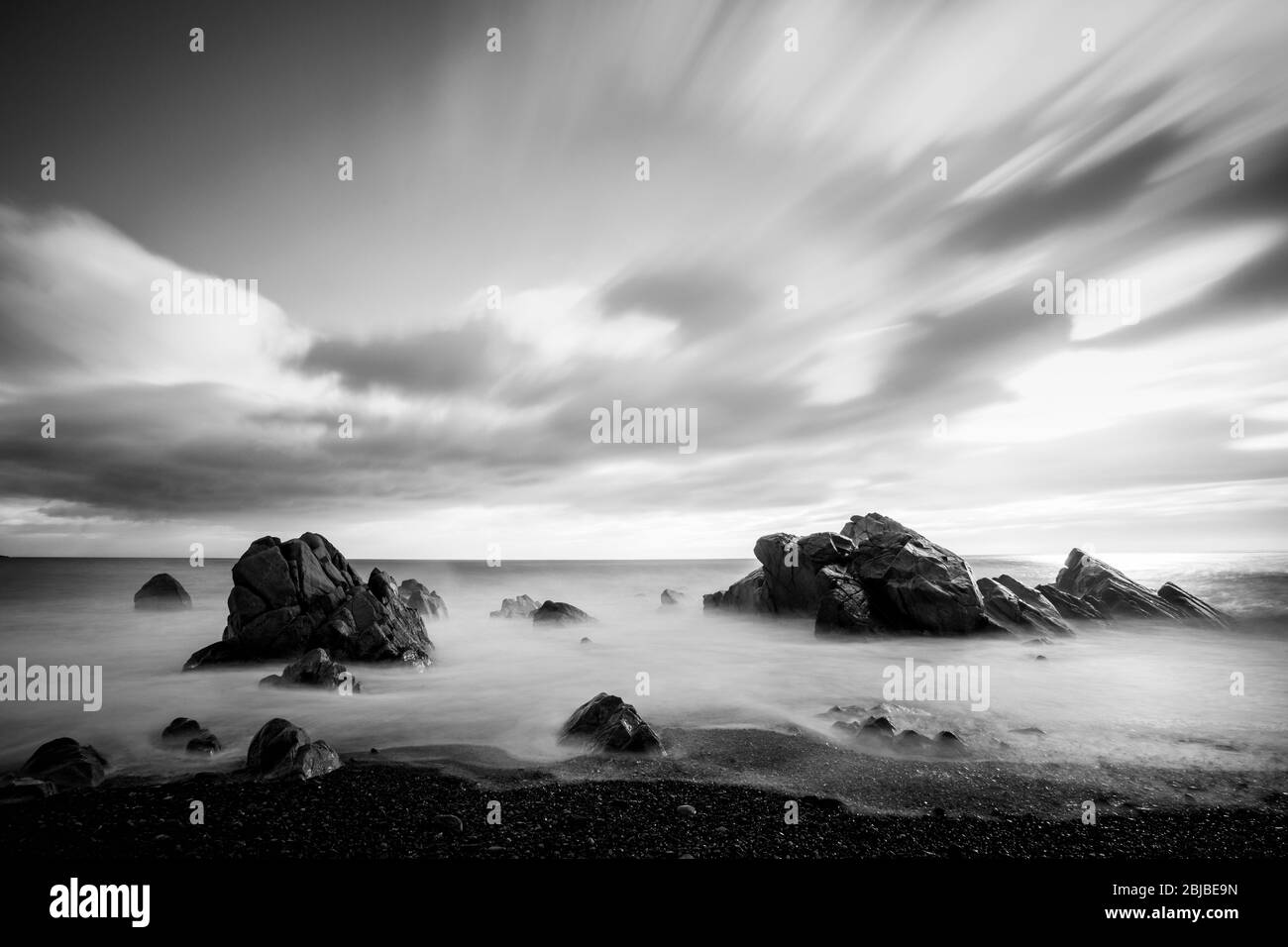 Nero / bianco, bello scenario di rocce e cielo drammatico sul mare con lunga esposizione, Corea del mare orientale Foto Stock