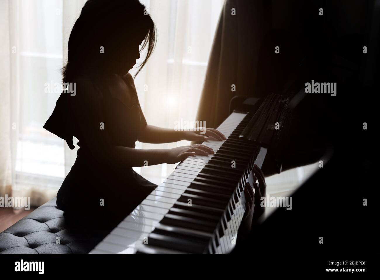 i bambini silhouette che giocano al pianoforte hanno talento e si esercitano per aumentare le capacità musicali per l'occupazione futura. Foto Stock