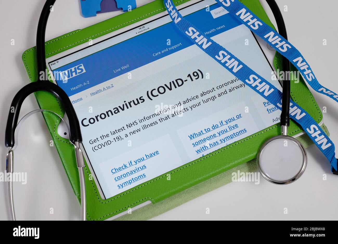 informazioni su coronavirus covid-19 sul sito web nhs su tablet con cordino e stetoscopio Foto Stock