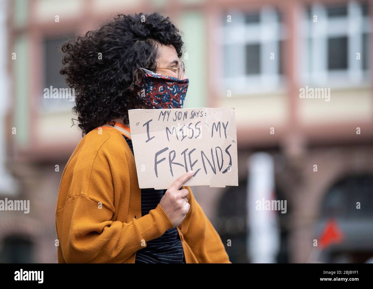 29 aprile 2020, Hessen, Francoforte sul meno: Una giovane donna mostra un poster con l'iscrizione 'mio figlio dice: Mi manca i miei amici' a una protesta sulla Römerberg. Madri, padri e figli hanno dimostrato il rispetto dei diritti dei bambini durante la pandemia di Corona. Foto: Boris Roessler/dpa Foto Stock