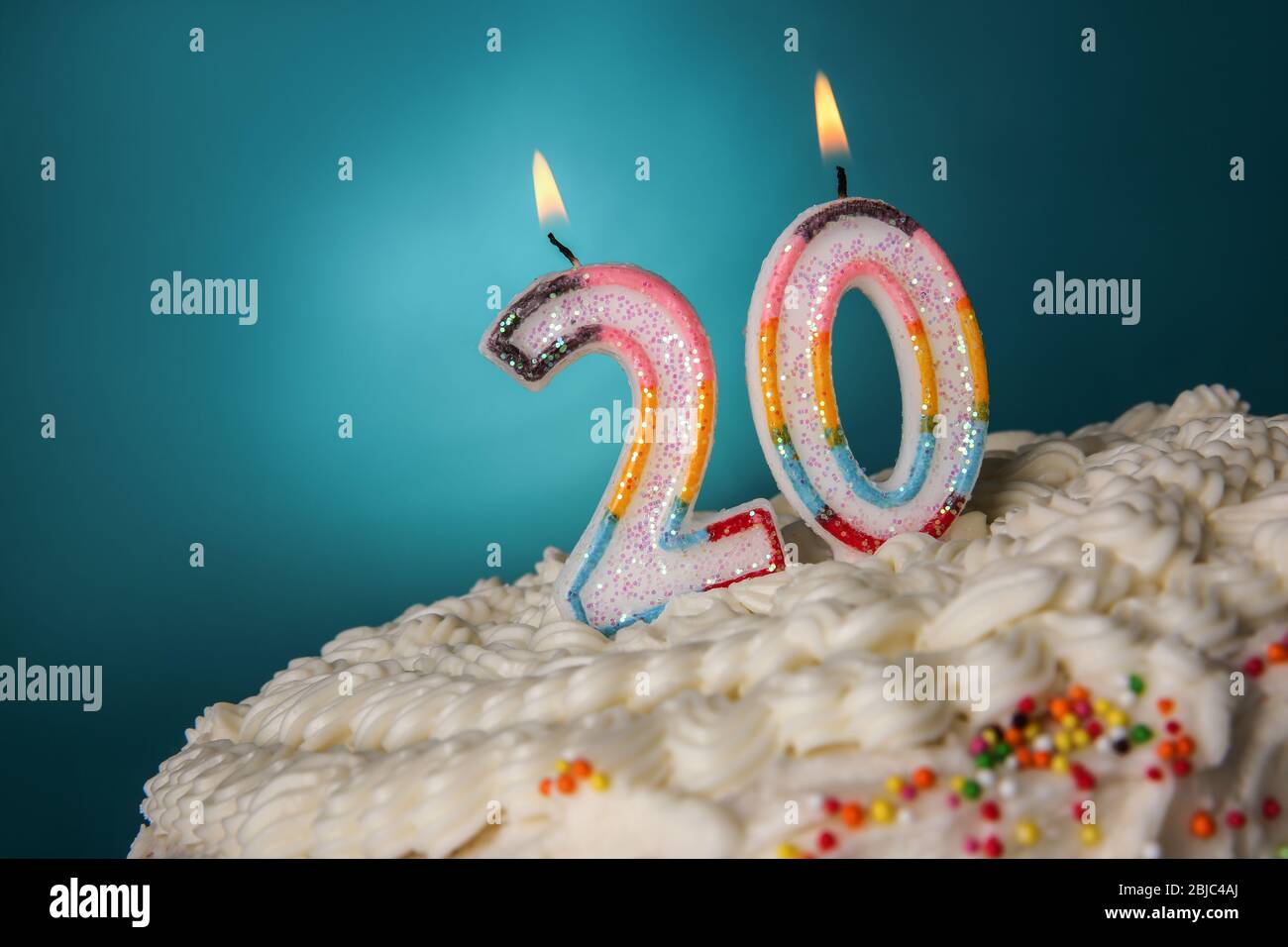 Torta gustosa con candele per il ventesimo compleanno su sfondo blu Foto Stock
