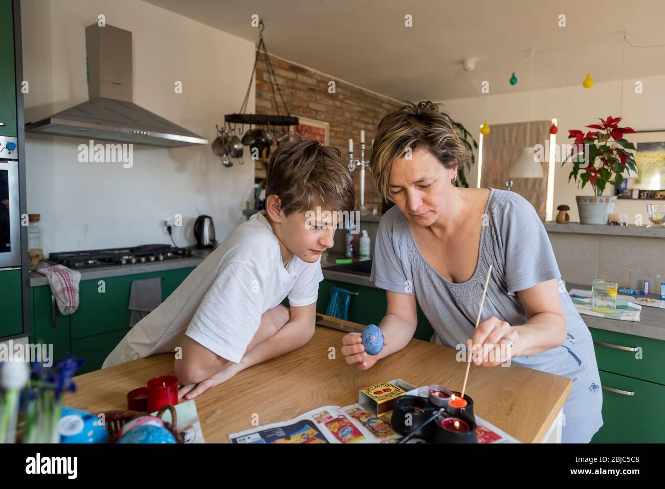 Madre e figlio che colorano l'uovo di Pasqua a casa in cucina Foto Stock