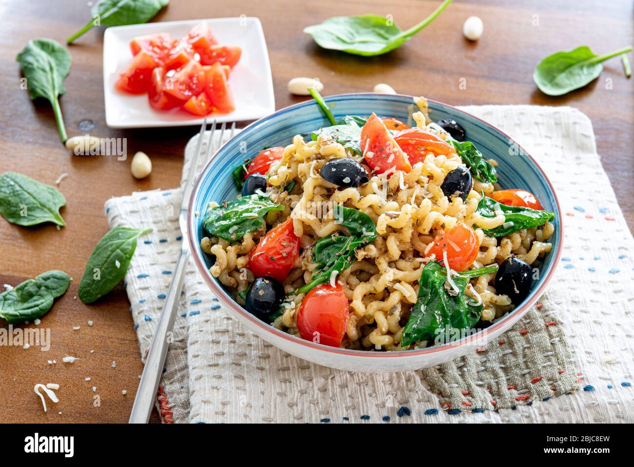 Fusilli lunghi, pomodoro di ciliegia, olive nere e spinaci, cibo mediterraneo per la dieta. Foto Stock