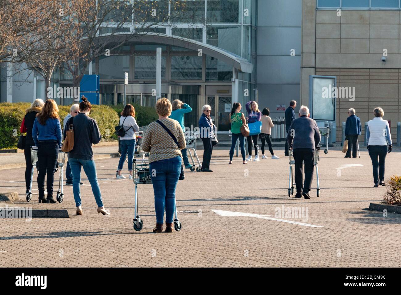 La gente aspetta in fila in coda per un supermercato durante il blocco del coronavirus Foto Stock