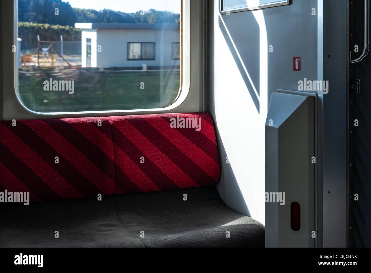 Giappone, vista dall'interno di un treno rurale giapponese. I posti a sedere e una vista della campagna fuori dalla finestra Foto Stock