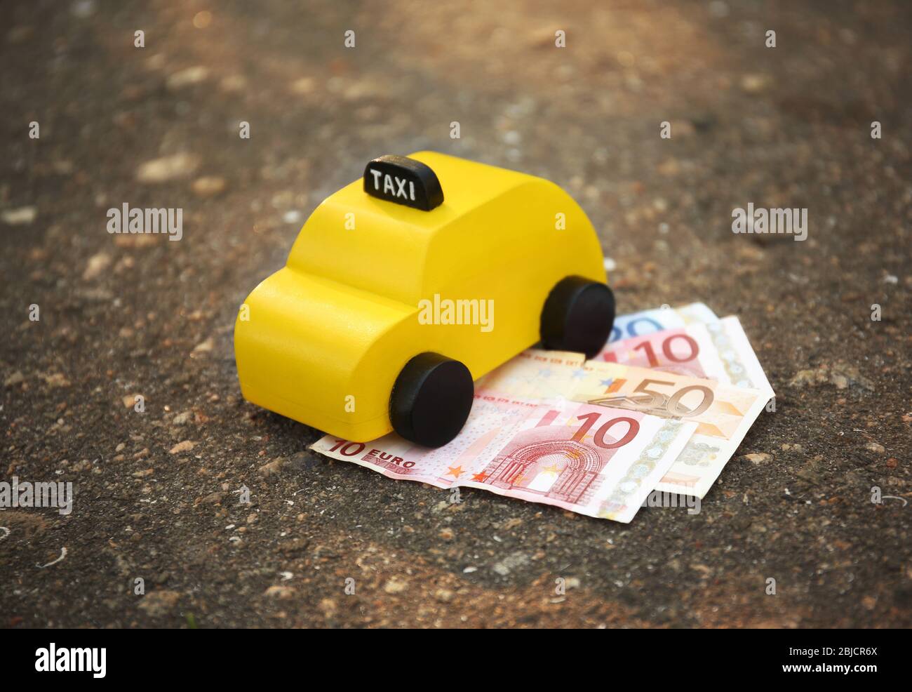 Taxi giocattolo giallo con soldi a terra Foto Stock