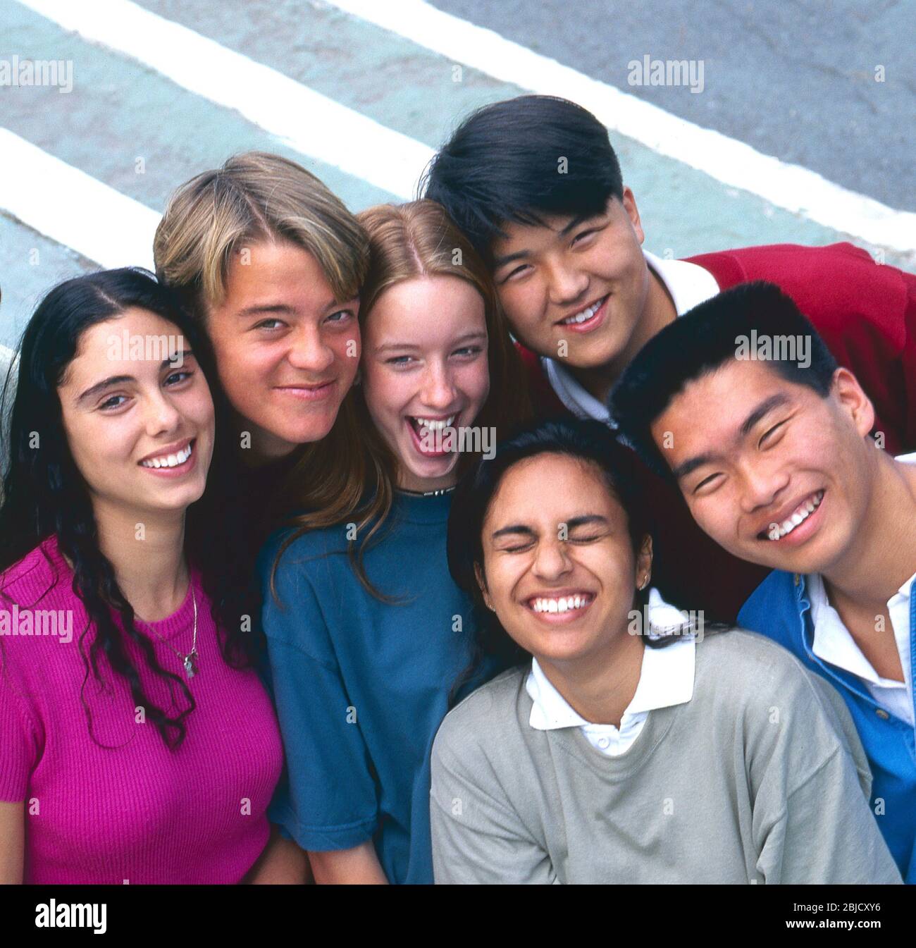Scuola studenti multiculturale gruppo di 6 felice attraente adolescente scuola superiore scuola superiore scuola multiculturale studenti in t camicie colorate squash insieme e posa al di fuori in un ambiente soleggiato università campus Foto Stock