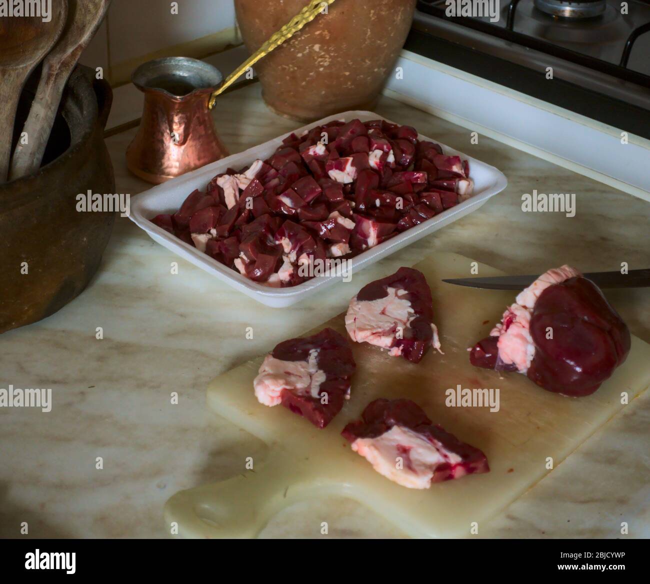 Affettare la carne di fegato su tagliere a Ramadan con attrezzi storici della cucina sullo sfondo Foto Stock