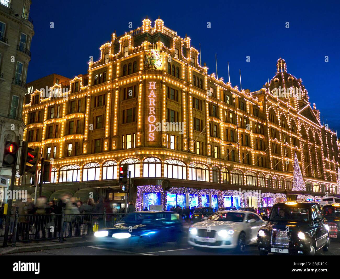 HARRODS NOTTE NATALE ACQUIRENTI LUCI SFOCATE TRAFFICO Harrods grande magazzino al crepuscolo con luci di Natale acquirenti e passando traffico sfocato Knightsbridge Londra SW1 Foto Stock
