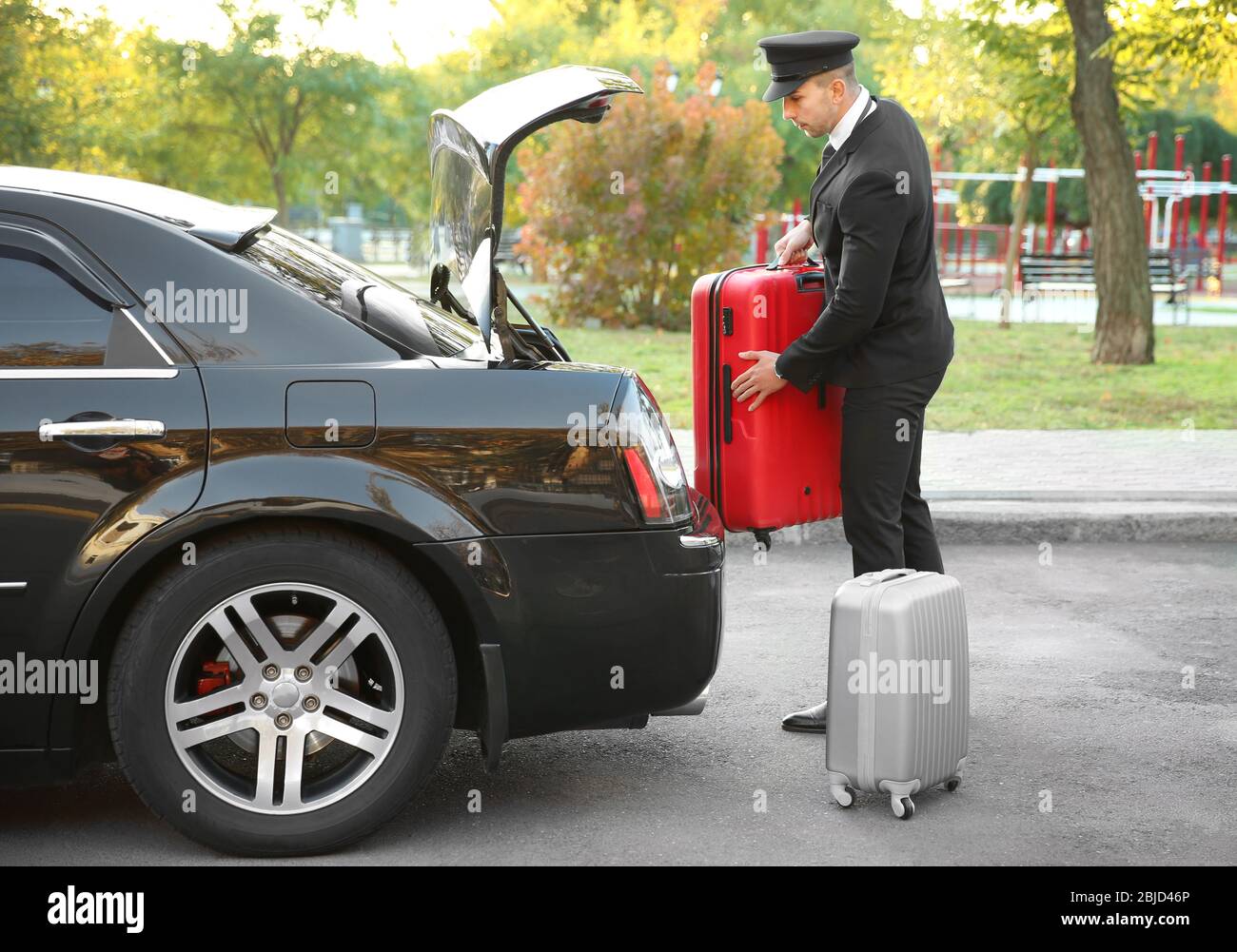 Autista che mette la valigia nel bagagliaio dell'auto Foto Stock
